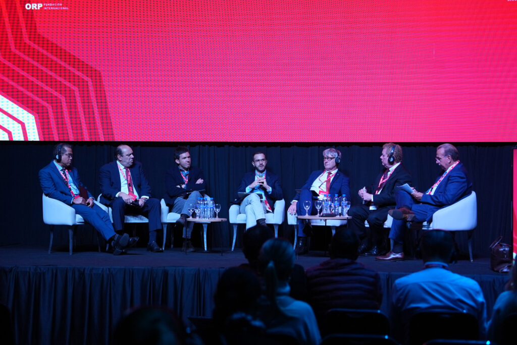 Mesa de debate con siete participantes que usan auriculares de traducción simultánea
